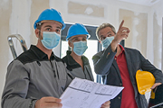 Besprechung von Technikern mit Plan auf einer Baustelle